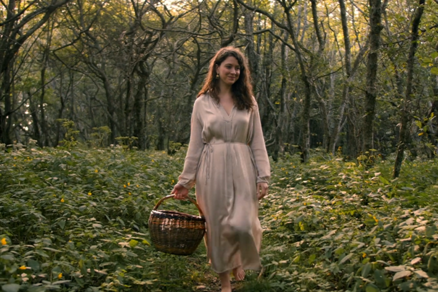 A woman walking with a basket down a path in the woods