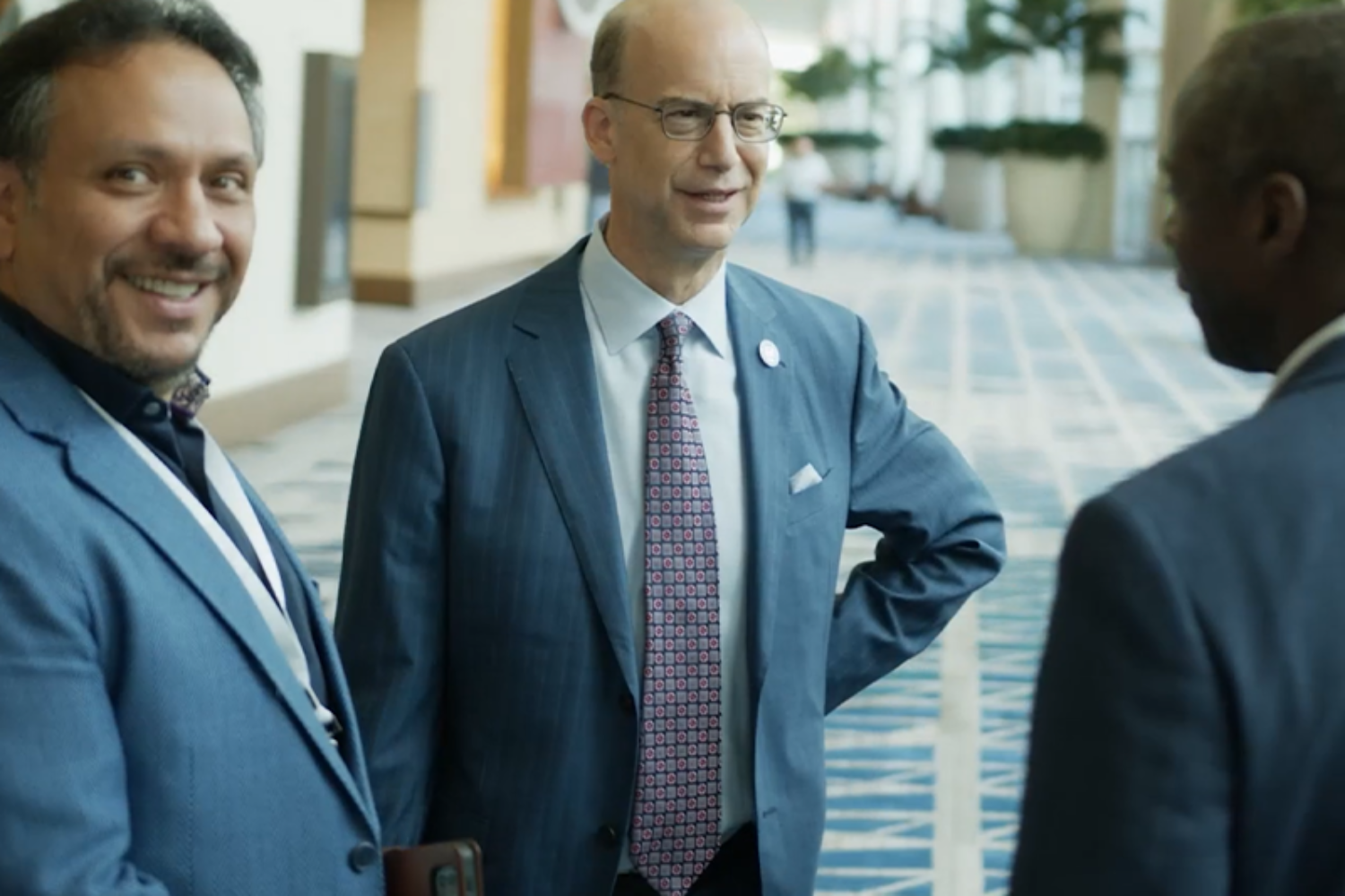 Three men interacting at a corporate conference event